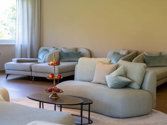 Auf in ein romantisches Hotel in Tirol Moderne Wohnzimmer mit bequemen Sofas, Kissen und einem dekorativen Tisch mit Obst