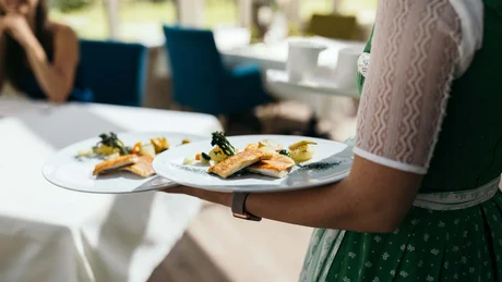 Kellnerin trägt Teller mit feinem Fischgericht in einem Restaurant