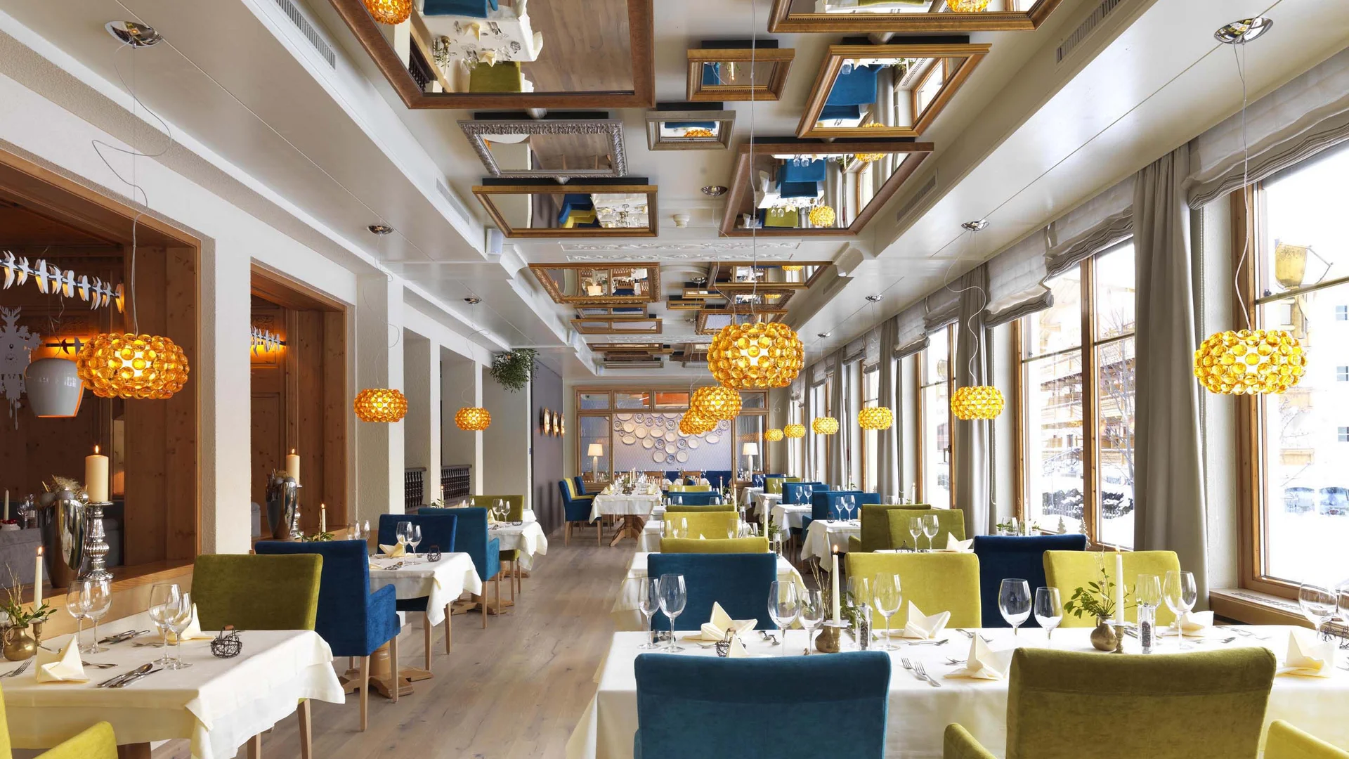 Kulinarik im Wiesenhof: Restaurant in Pertisau Helles Restaurant mit grünen und blauen Stühlen und Pendelleuchten