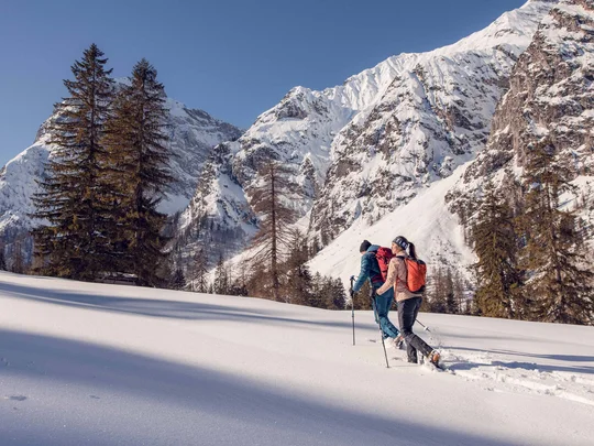 Wanderhotel Tirol: durchs Karwendel wandern und biken Zwei Personen wandern mit Schneeschuhen in verschneiter Berglandschaft