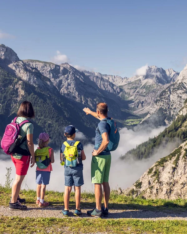 Familie mit Rucksäcken genießt Bergblick bei Wanderung in den Alpen
