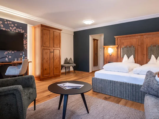 Zimmer und Suiten im Wiesenhof Gemütliches Hotelzimmer mit Doppelbett, Holzschrank und Fernseher an der Wand