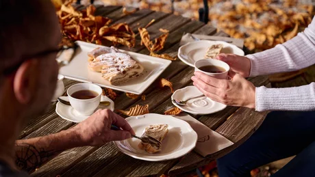 Zwei Personen trinken Kaffee und essen Kuchen im Freien im Herbst