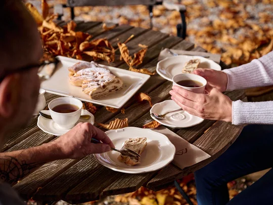 Zwei Personen trinken Kaffee und essen Kuchen im Freien im Herbst