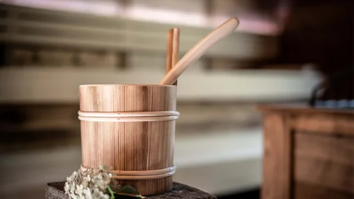 Der Wiesenhof in Pertisau und die Familie Entner mit Team Traditioneller Holzsaunabecher mit Schöpfkelle und Blume auf Stein