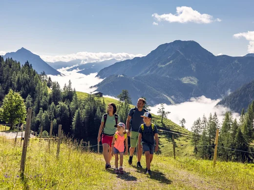 Familie wandert auf Bergweg mit Bergpanorama und Wolken in der Ferne