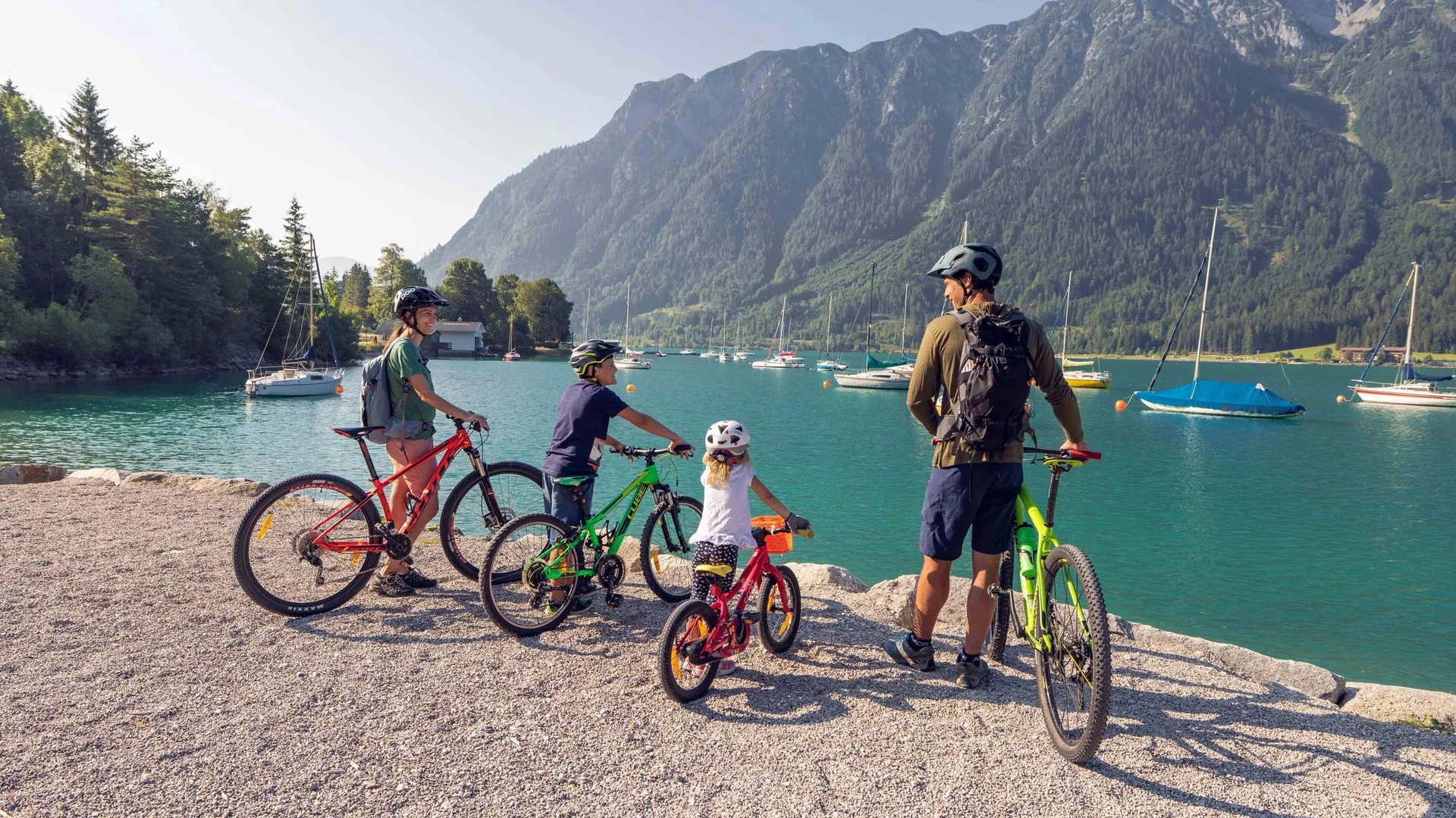 Euer Familienhotel am Achensee Familie mit Fahrrädern am See vor Bergen und Segelbooten