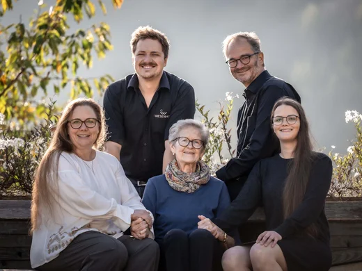 Der Wiesenhof in Pertisau und die Familie Entner mit Team Fünf Familienmitglieder sitzen lächelnd im Freien und halten sich an den Händen
