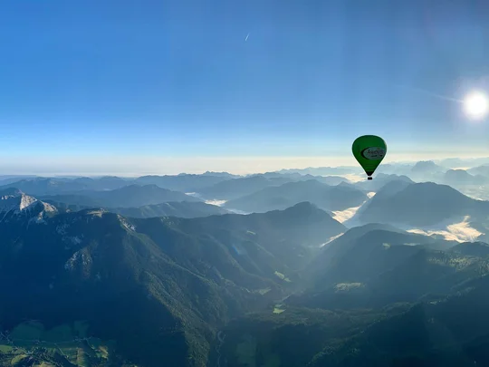 Sehenswürdigkeiten am Achensee rund um den Wiesenhof Grüner Heißluftballon über nebligen Bergen bei klarem Himmel und Sonne