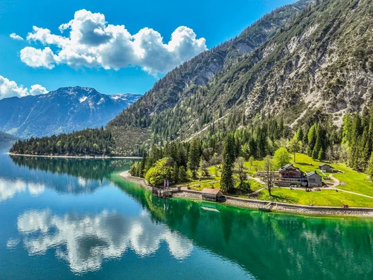 In, auf und rund um den Achensee Bergsee mit blauem Himmel, Wolken und Häusern am Ufer