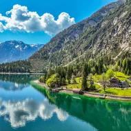 Den Achensee entdecken Bergsee mit blauem Himmel, Wolken und Häusern am Ufer