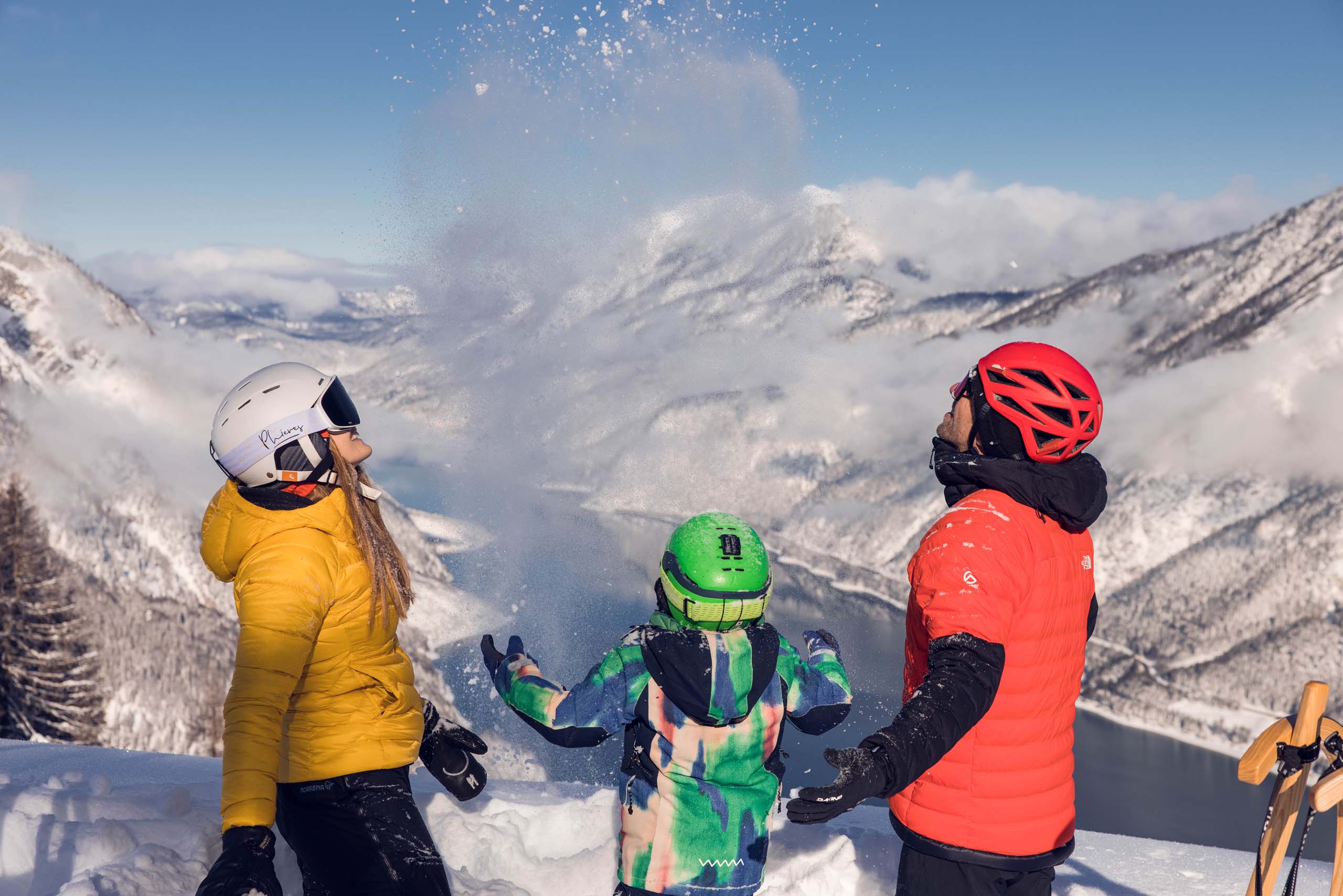Euer Familienhotel am Achensee Drei Personen mit Skihelm werfen Schnee in den Bergen