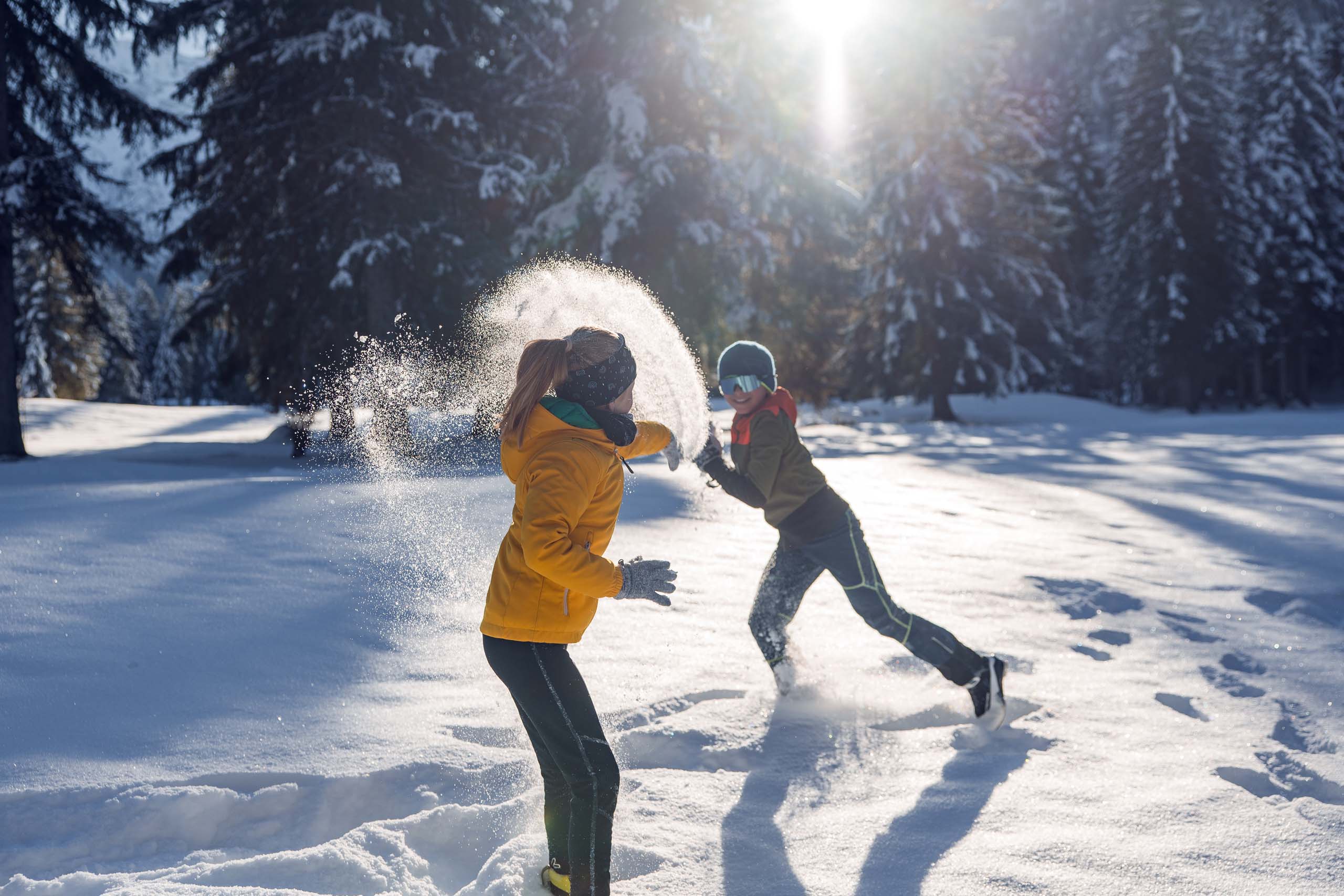 Euer Familienhotel am Achensee Kinder spielen im Schnee in einem sonnigen verschneiten Wald
