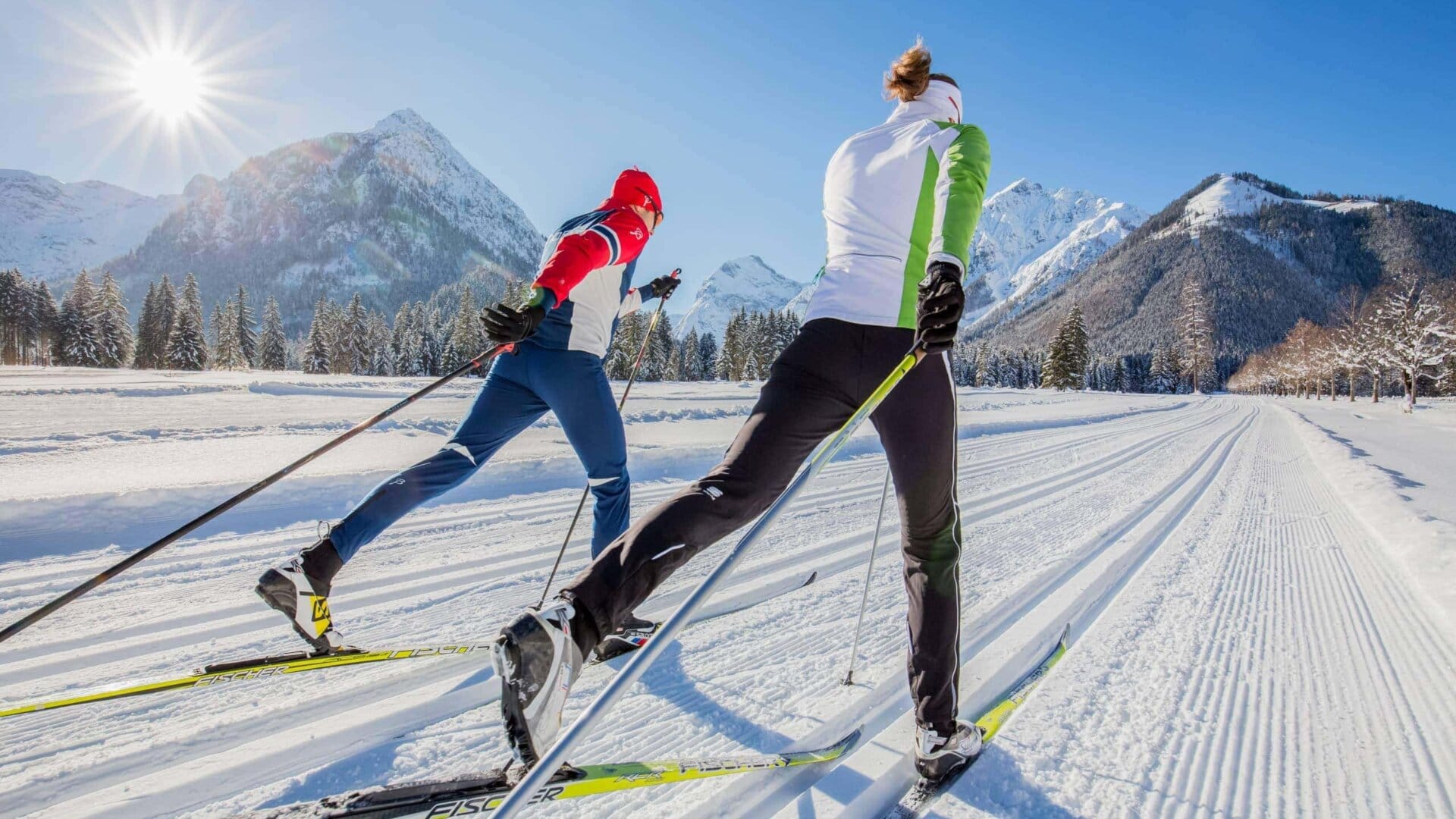 Zwei Skifahrer beim Langlauf in den Bergen.