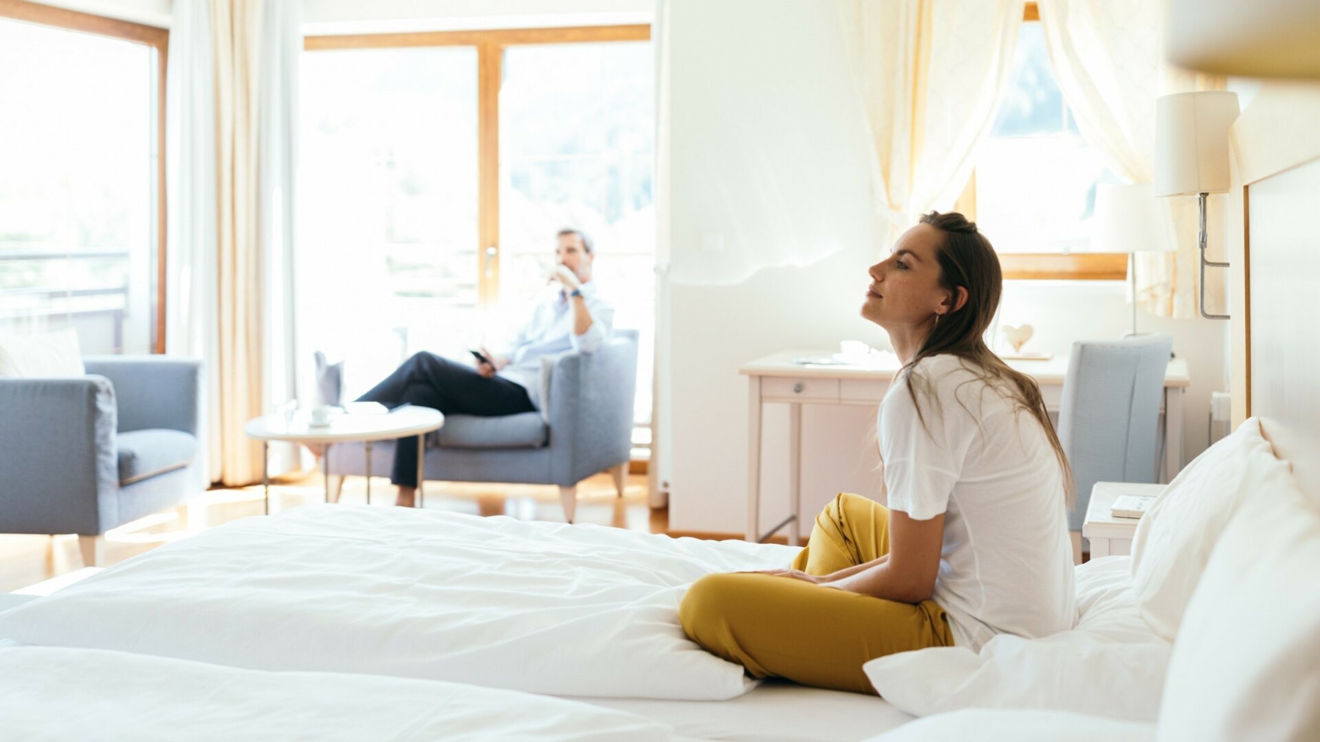Frau sitzt nachdenklich im Hotelzimmer.