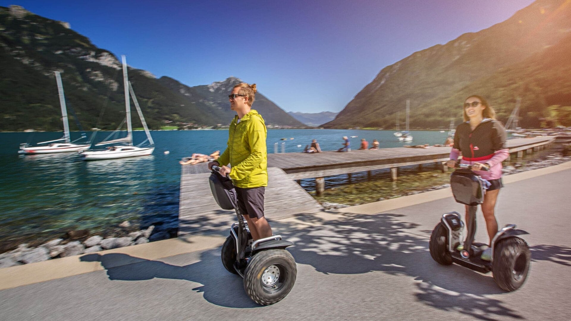 Zwei Personen fahren mit Segways am See.
