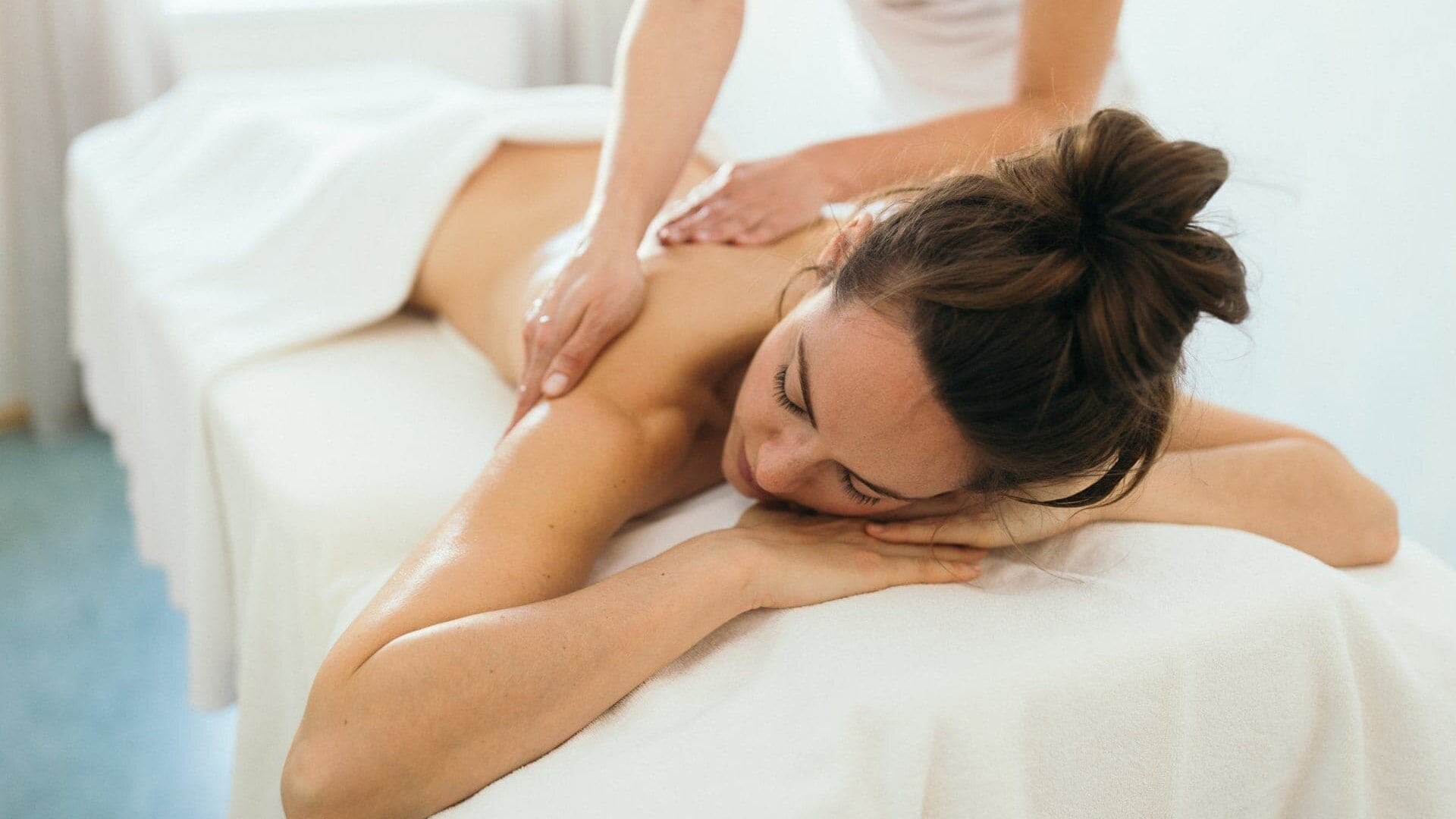 Frau erhält entspannende Massage auf Tisch.