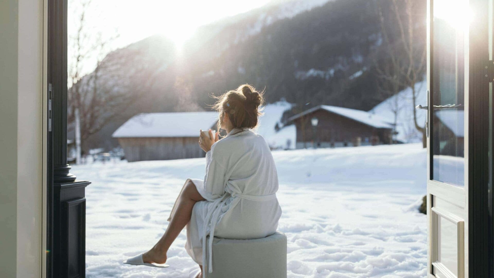 Frau mit warmem Getränk vor verschneiter Landschaft