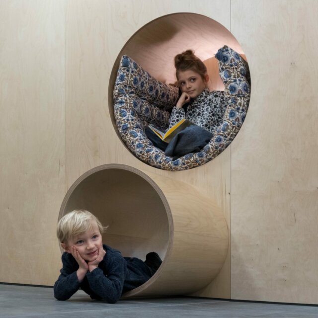 Kinder in kreativen Holzspielstrukturen.