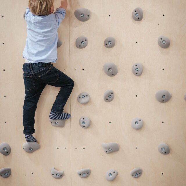 Kind klettert an einer Kletterwand.