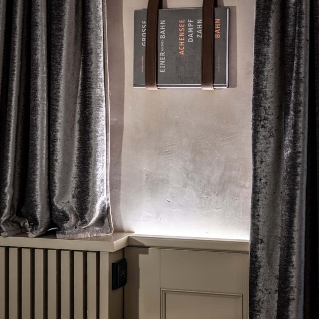 Bücher in einem stilvollen Innenraum, neben Vorhängen.