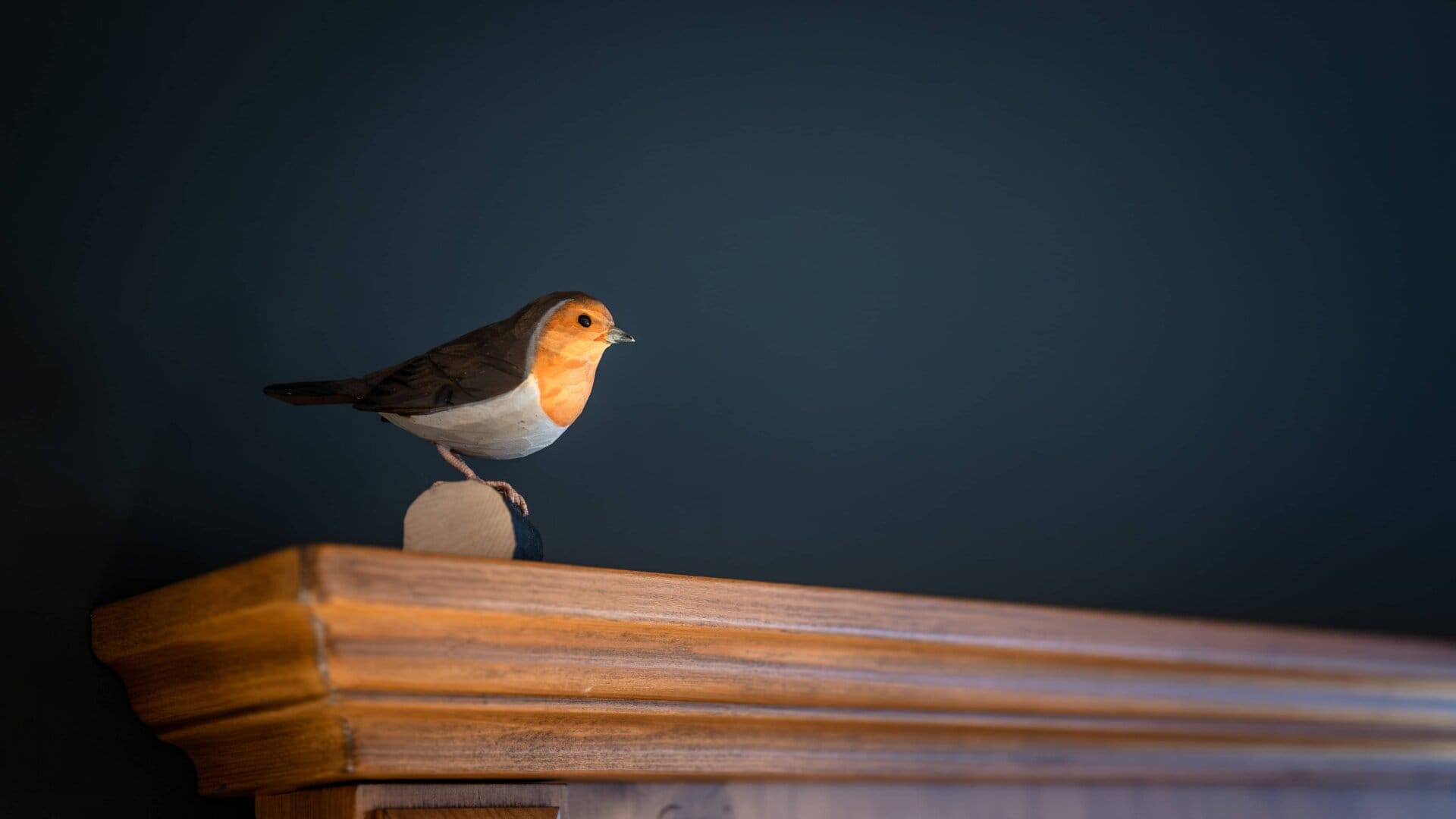 Holzfigur eines Vogels auf einem Regal