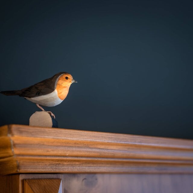 Holzfigur eines Vogels auf einem Regal