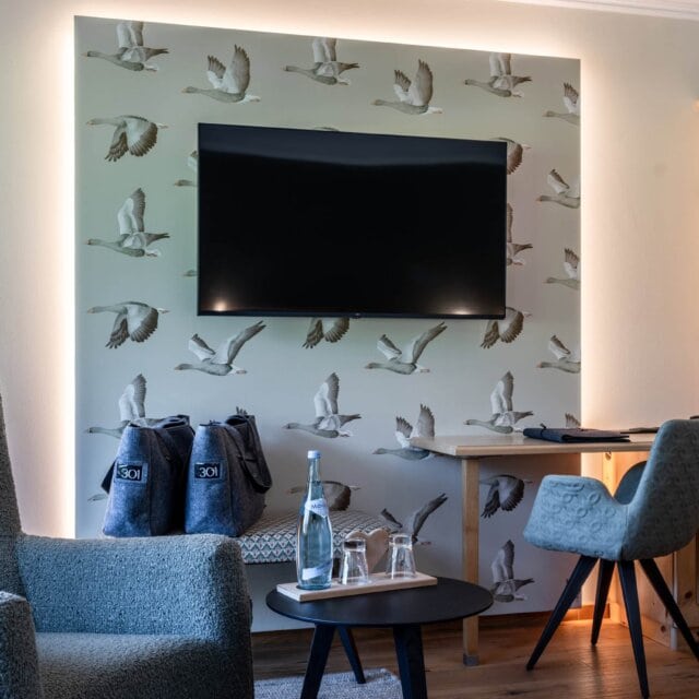 Gemütlicher Raum mit TV und Vogelmotiv-Tapete.