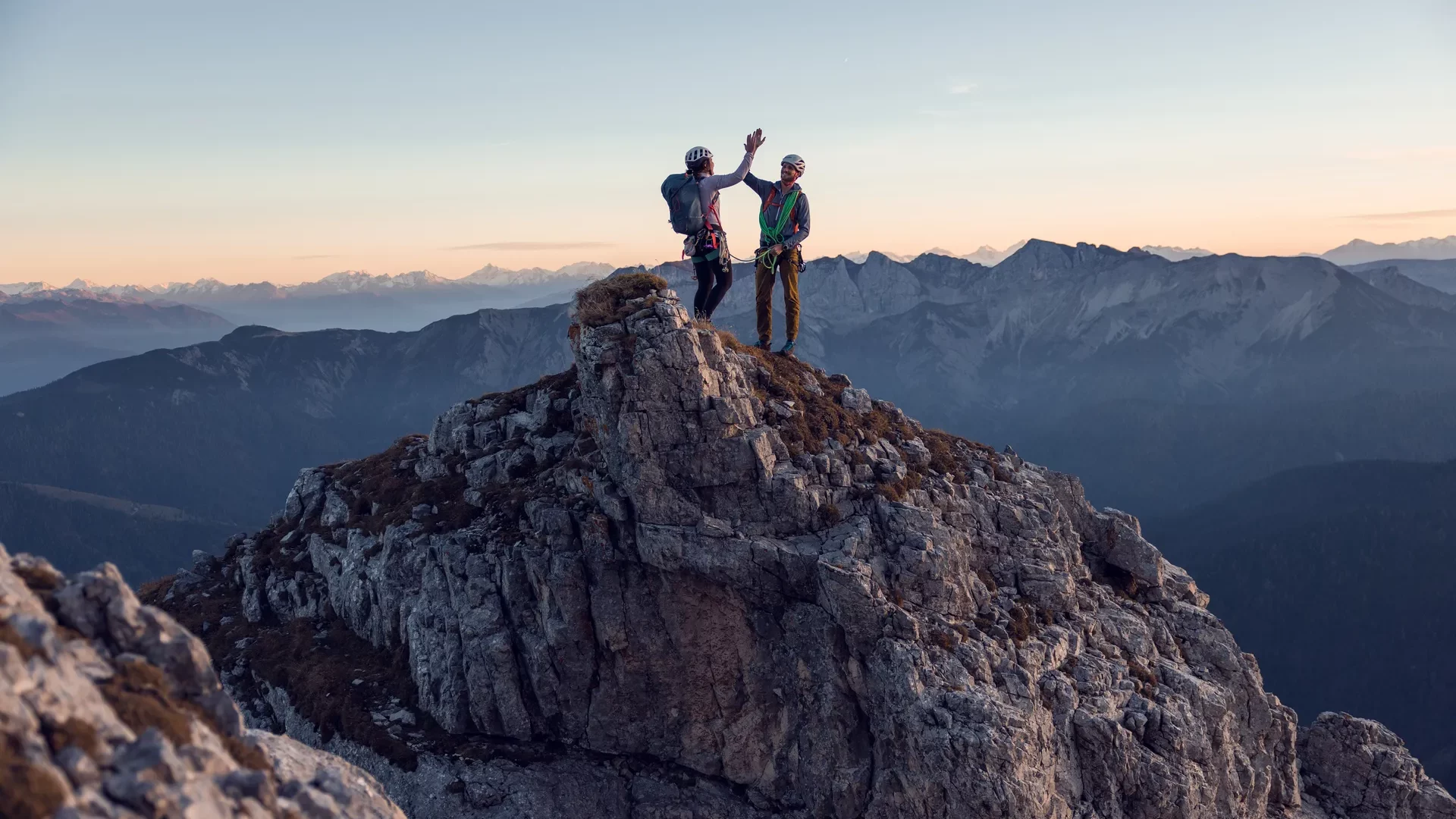 Zwei Bergsteiger auf einem Gipfel gemeinsam feiern.